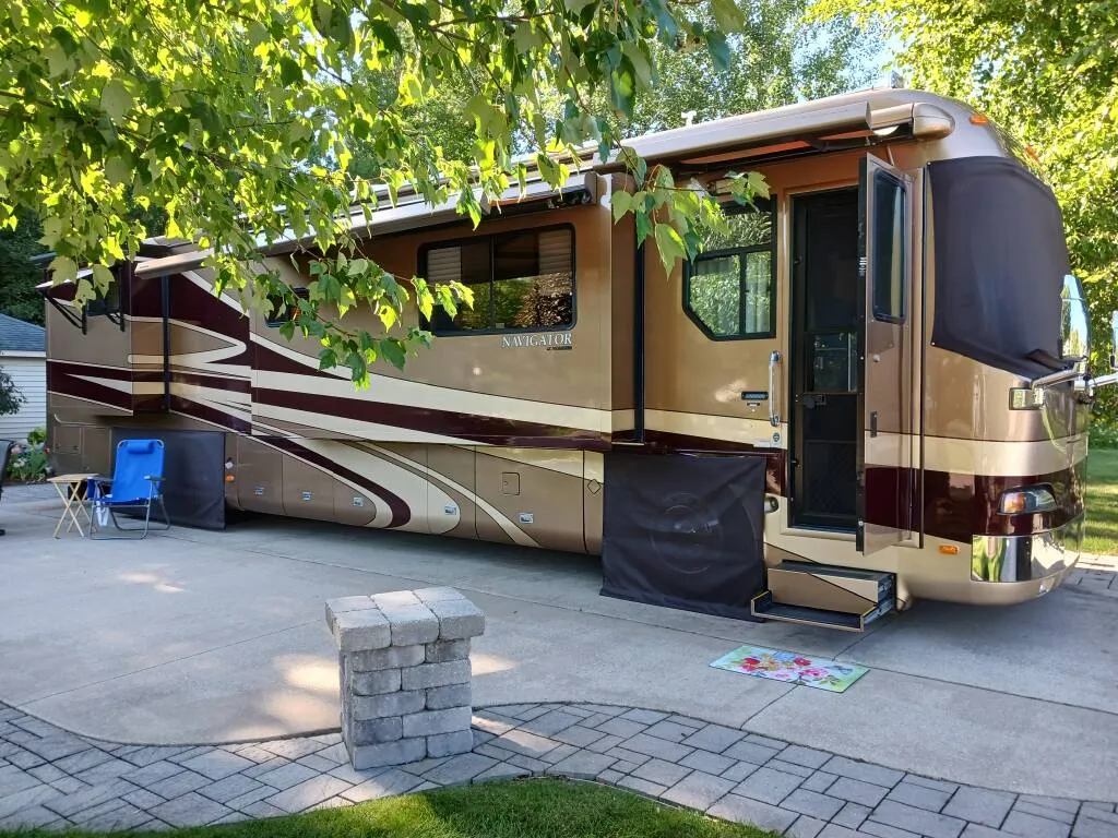 Luxury Class A dual axle motorhome being serviced by a technician in a clean workshop setting